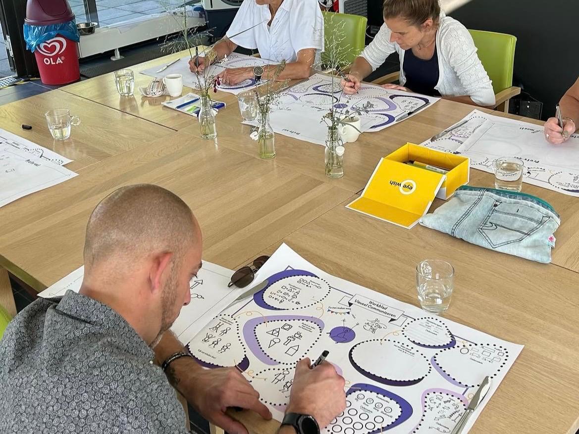 Deelnemers vullen werkbladen in tijdens een workshop visueel communiceren
