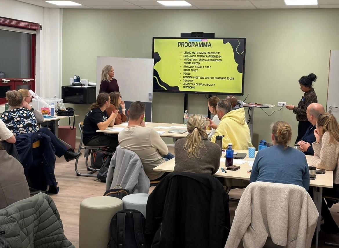 Trainer geeft uitleg bij het programma van een workshop tekenen en praatplaat maken